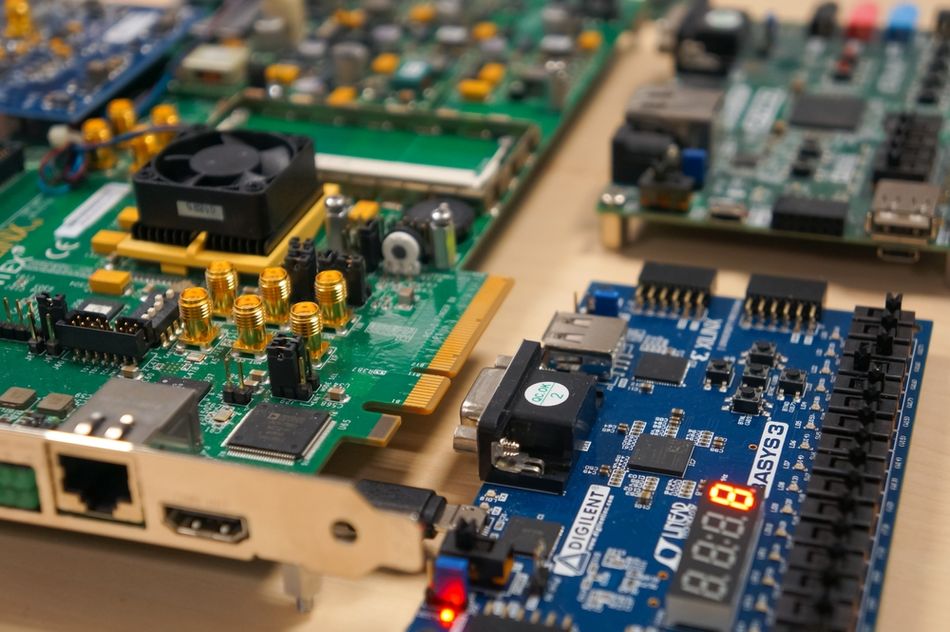 Detail of two FPGA boards in an engineering school: gold SMA connectors on a Xilinx Kintex motherboard, VGA socket and seven-segment display on a Digilent Basys3