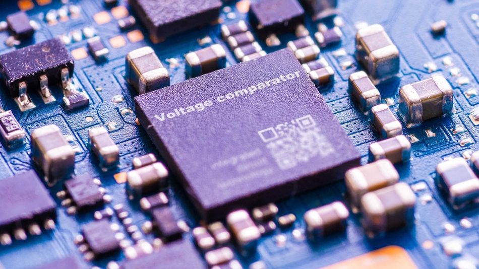 Close-up photograph of an integrated circuit mounted on a printed circuit board surrounded by surface-mount components, representing precision analog electronics and voltage reference applications.