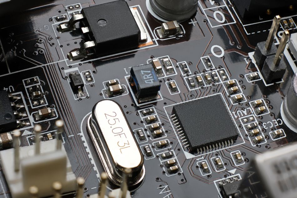 Close-up of a printed circuit board showing a quartz crystal oscillator marked 25.0 MHz positioned next to a microcontroller and surrounding electronic components used for clock generation and timing control.