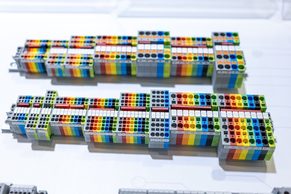 Close-up of multiple color-coded DIN rail terminal blocks arranged in a row, showing modular connection points used to organize and distribute electrical circuits within a control panel.