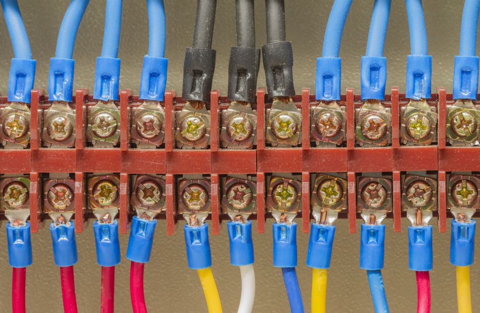 Close-up of electrical wiring and conductor terminations inside a machine control enclosure, showing multiple insulated wires routed between terminal connections and other electrical components.