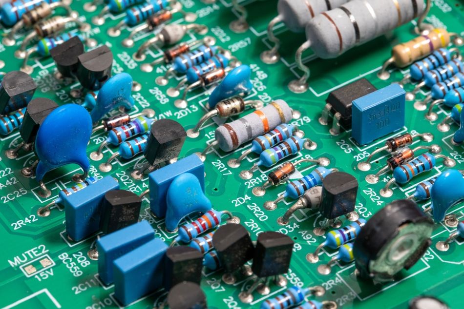 Close-up photograph of an electronic circuit board populated with transistors, resistors, capacitors, and other electronic components connected through conductive traces. Transistors are semiconductor devices that control or amplify electrical signals, while resistors limit current and capacitors store and release electrical energy. Together, these components help electronic circuits perform functions such as signal processing, power regulation, and control.