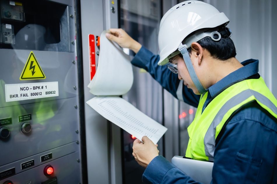Engineer Inspecting a Control Panel Room with Safety Documents